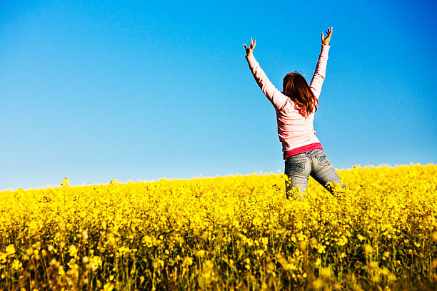 istock Woman jumps for joy in canola field 114324393
