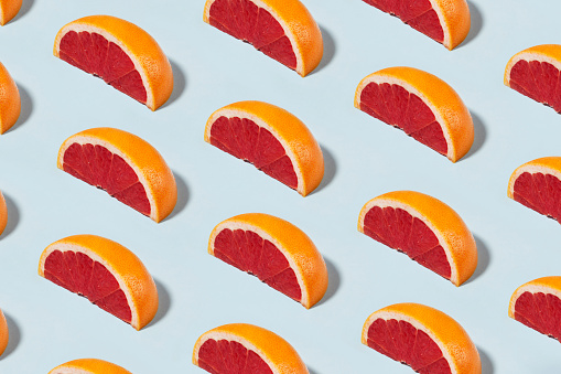 Fruit pattern with half slices of grapefruit on soft blue pastel background