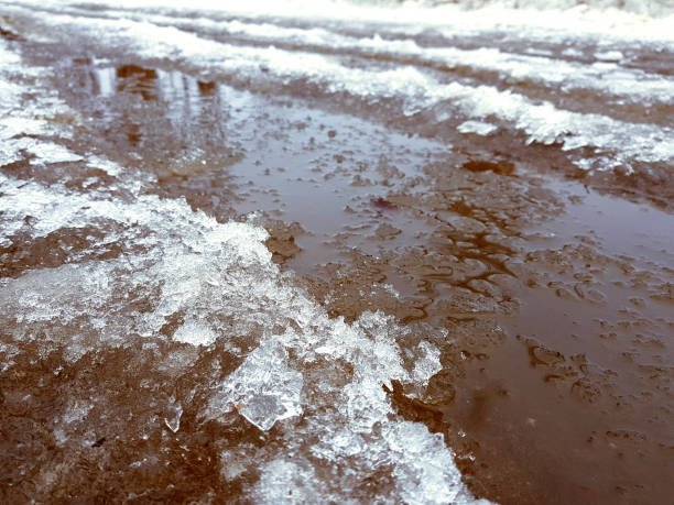 istock Beautiful puddles with ice crust, snow and reflection in winter or spring 1143244184