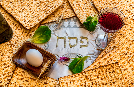 Traditional unleavened bread food - matzah and glass of red wine for Jewish Passover Holiday. Festive serviette with written in Hebrew letters meaning Pesah or Pesakh or Jewish Passover