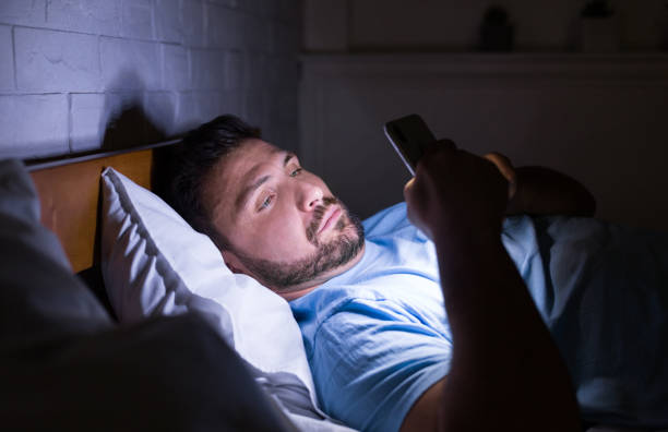 mann plaudert spät in der nacht auf smartphone - working bed smart phone bedroom stock-fotos und bilder