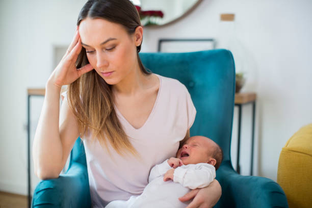 Stressed Mother Holding Crying Baby Suffering From Post Natal Depression At Home Stressed Mother Holding Crying Baby Suffering From Post Natal Depression At Home postpartum depression stock pictures, royalty-free photos & images