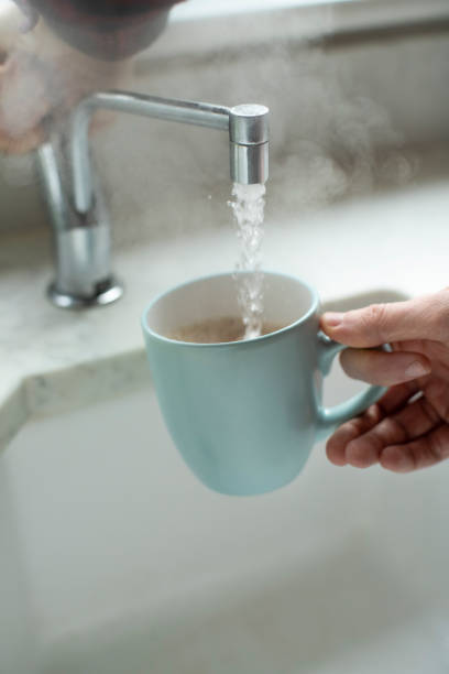 沸騰水の蛇口から熱い飲み物を作る男のクローズアップ - heat water faucet water pipe ストックフォトと画像