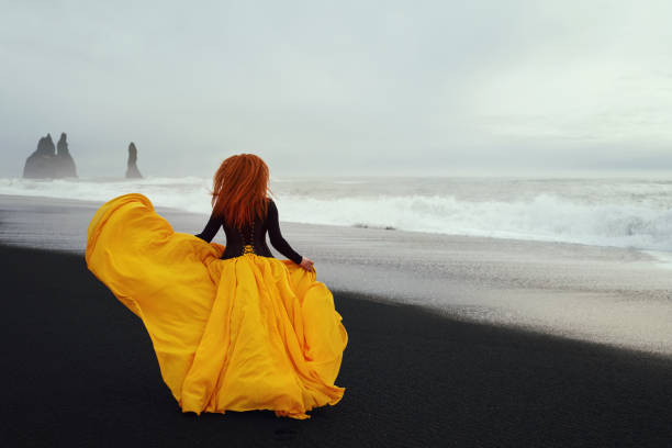 running on the beach in cold day, fashion model with yellow flying dress.photo taken on Reynisfjara beach.