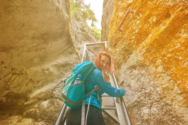 rear view of hiker woman looking over the shoulder and moving up on metallic stairs.