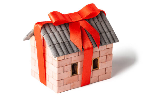 istock House wrapped as a gift in red ribbon with bow isolated on white background. 1143249824