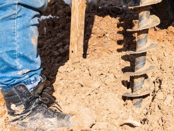 人間は地質学的に井戸を掘削する。ブーツ、スクリュー、土壌のクローズアップ - borehole ストックフォトと画像