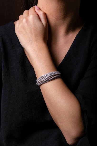 istock Silver female bracelet on hand with diamonds on a black background. 1143251352