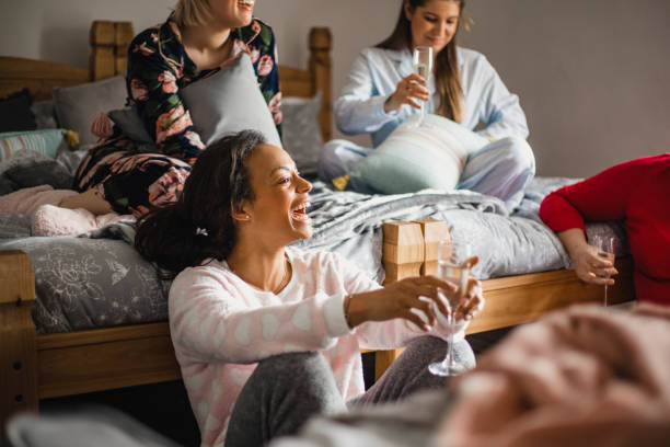 Having Fun with Friends Small group of female friends relaxing and talking while enjoying a girls night in. They are sitting in a bedroom in their pyjamas. ladies night stock pictures, royalty-free photos & images
