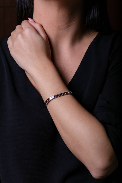 istock Silver female bracelet on hand with stone on a black background. 1143252073