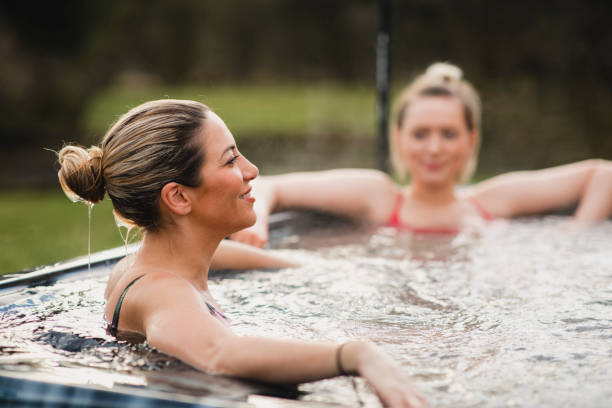 Relaxing in the Hot Tub Mid adult woman relaxing in a hot tub with her friends. hot tub stock pictures, royalty-free photos & images