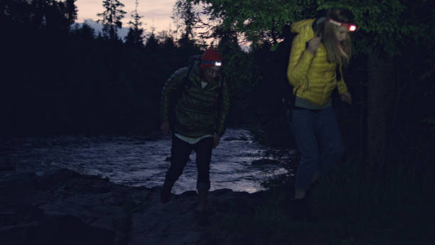 istock Young couple crossing mountain stream together. Night trip 1143253633