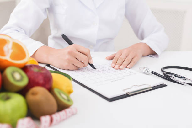 istock Female nutritionist doctor writing vegetable diet plan 1143255261