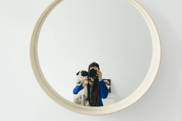 Young woman and a small pug capturing themselves in the mirror by professional mirror camera