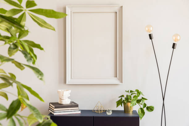 istock Scandinavian and design home decor with mock up gray poster frame, navy blue shelf with stylish accessories, lamp and plants. Stylish and minimalistic room interior with big plant. Template. Blank. 1143256145