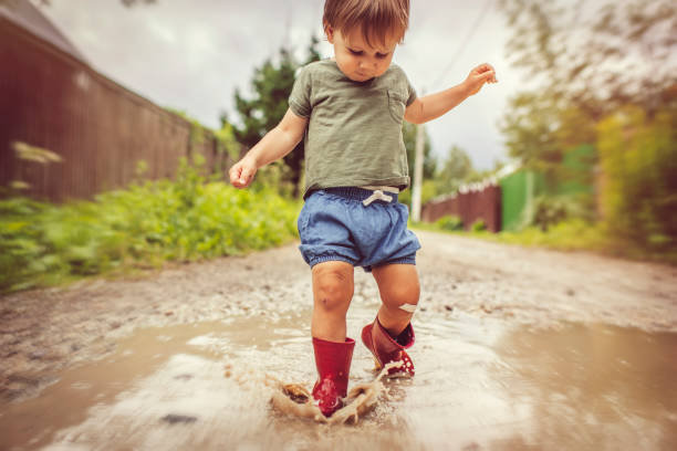 istock Little boy playing in puddle in a rainy day 1143257651