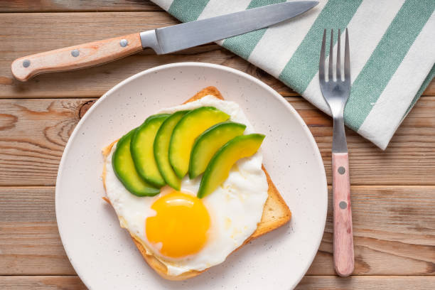 istock Toast bread with fried eggs, avocado. And cucumber slices on wooden table. 1143258348