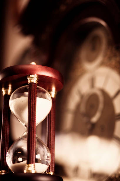 istock Hourglass with out of focus clockface in background, vertical 114325844