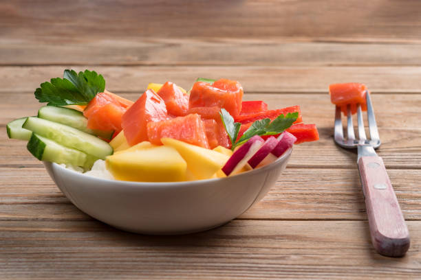 Poke salad from hawaii with fork on wooden background. Close up. Soft focus. T