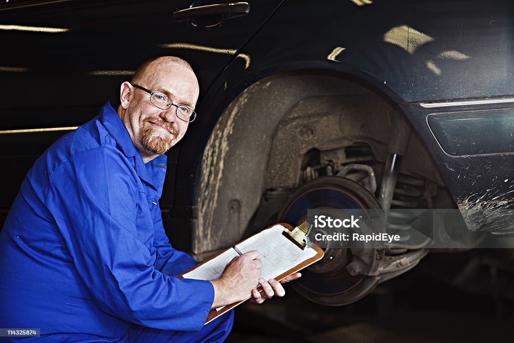 Souriant Mécanicien auto Inspecteur/chef de sa voiture roue hub - Photo de Examiner libre de droits