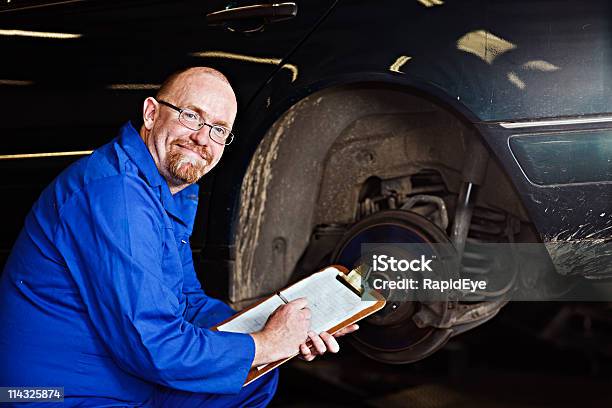 Photo libre de droit de Souriant Mécanicien Auto Inspecteurchef De Sa Voiture Roue Hub banque d'images et plus d'images libres de droit de Examiner