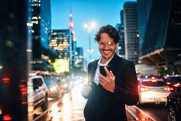 handsome businessman using his smartphone in the city smiling businessman in the city commuter photos stock pictures, royalty-free photos & images
