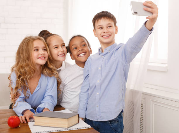 istock Happy kids taking selfie at school classroom 1143260088