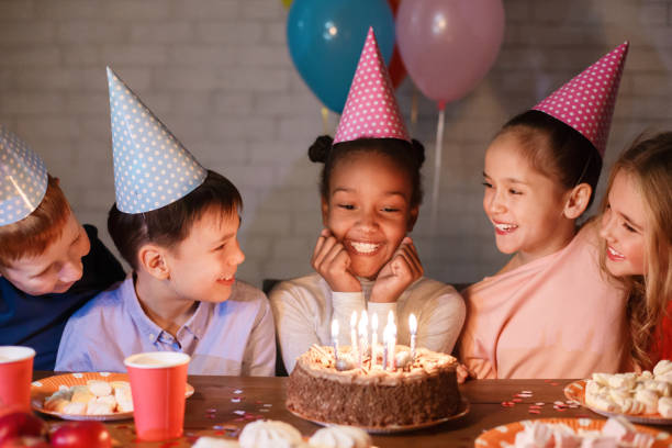 istock Kids celebrating birthday, looking at cake with candles 1143260093