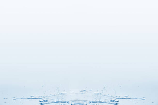 пролилась вода на стол с брызгами и каплями на бело-голубом фоне. - water puddle стоковые фото и изображения