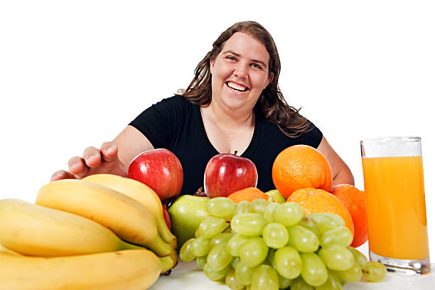 istock Plump young woman smilingly reaches for healthy fruit selection 114326131