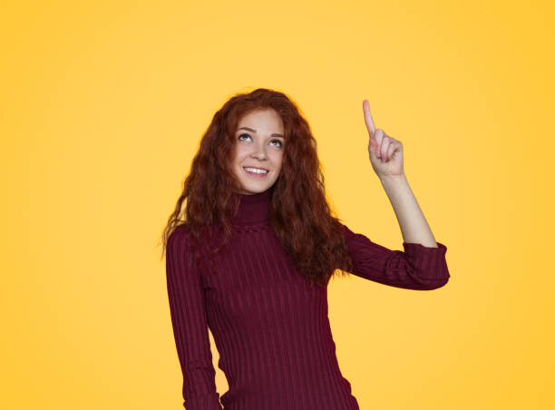 istock Young pretty woman pointing up in excitement 1143266110