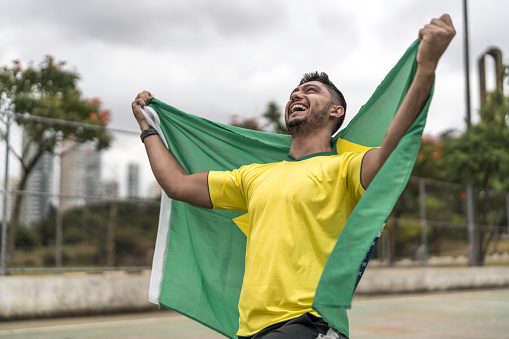 Male fan celebrating and holding brazilian flag