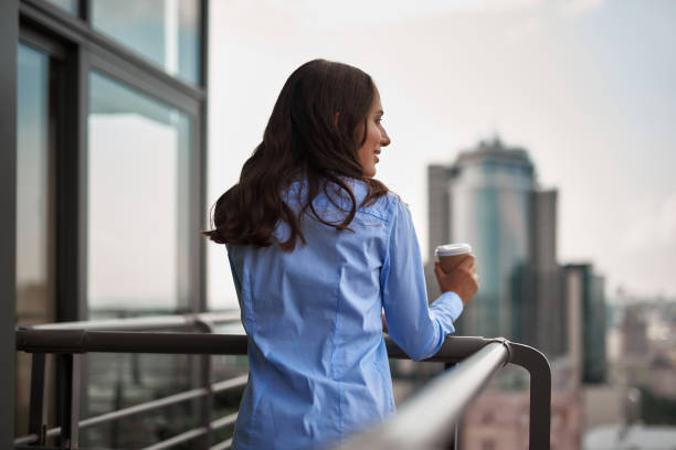 istock Female worker drinking coffee on office balcony 1143267593