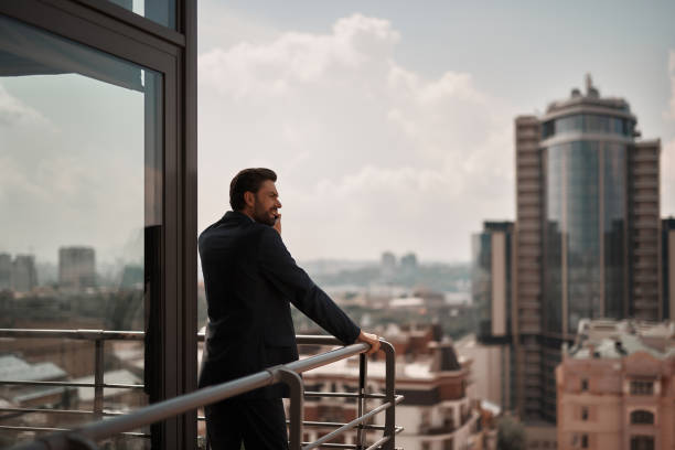 istock Man in office suit talking by phone on balcony 1143267640