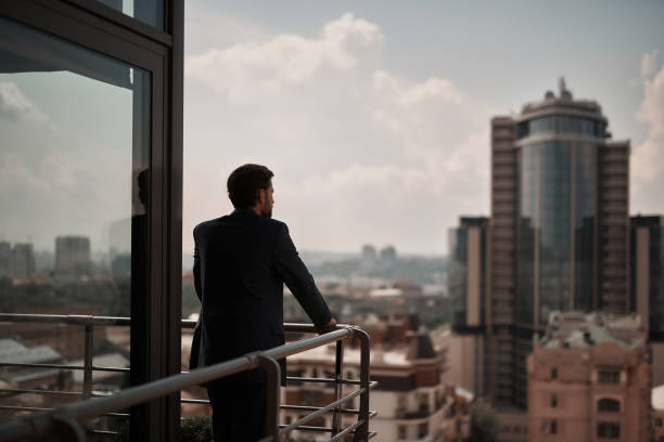 mâle dans le costume de bureau étant sur le balcon - rear view businessman thinking men photos et images de collection