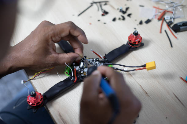 istock Black man mounting and soldering racing drone on wooden table 1143268931