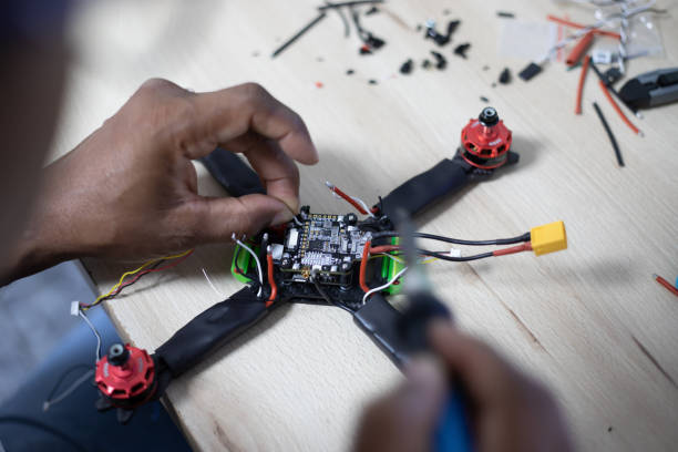istock Black man mounting and soldering racing drone on wooden table 1143268995