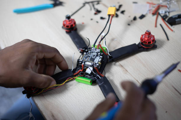 istock Black man mounting and soldering racing drone on wooden table 1143269064