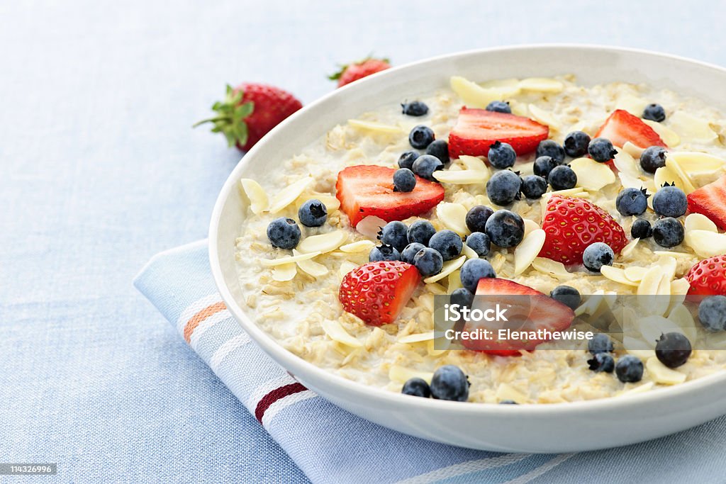 Oatmeal breakfast cereal with berries and almonds on linen Bowl of hot oatmeal breakfast cereal with fresh berries Oatmeal Stock Photo