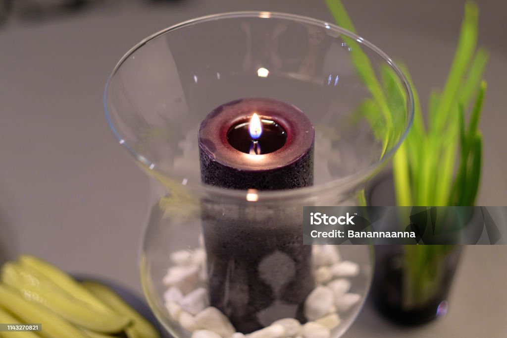 Decorative candle in a transparent glass vase Decorative candle in a transparent glass vase with small pebbles on the bottom Brown Stock Photo
