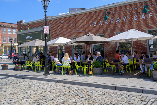 Fells Point, Baltimore, MD, USA -- April 13, 2019. Diners enjoy having coffee and breakfast outside in Fells Point, Baltimore on a spring morning.
