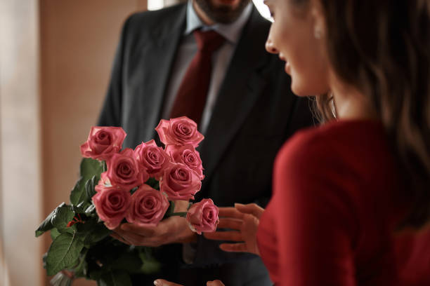 istock Young man presenting smiling woman pink roses 1143272274