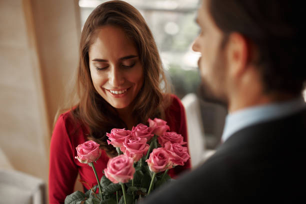 istock Young man in suit presenting lady bunch of roses 1143272317