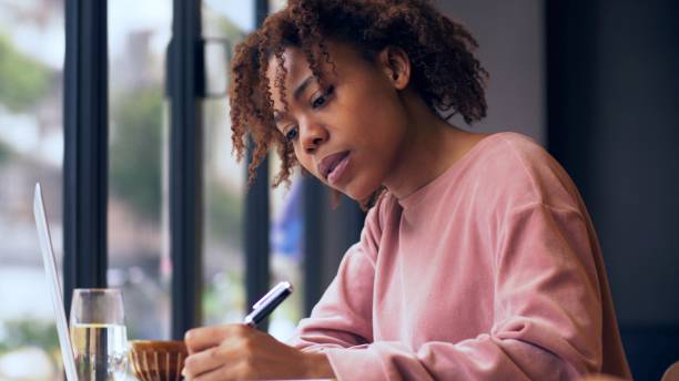 istock pretty young African woman writing indoor 1143273088