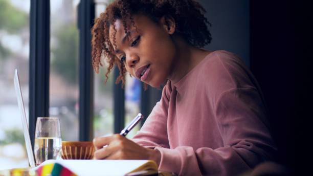 istock pretty young African woman writing indoor 1143273089
