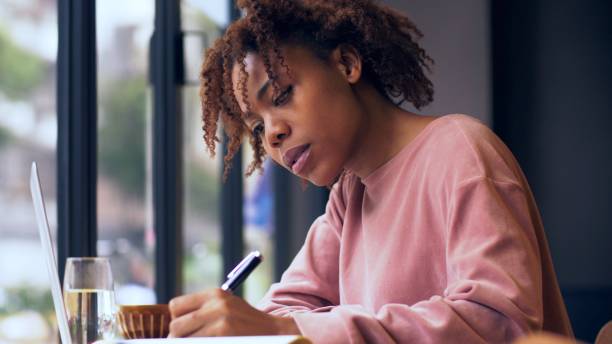 istock pretty young African woman writing indoor 1143273091