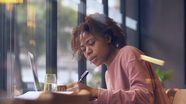 istock pretty young African woman writing indoor 1143273129