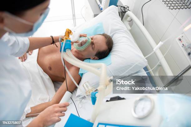 Male Patient Receiving Mechanical Ventilation In Intensive Care Ward Stock Photo - Download Image Now