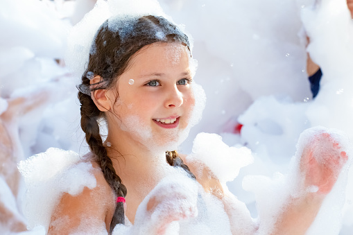 The girl is delighted with the foam at the foam disco for children