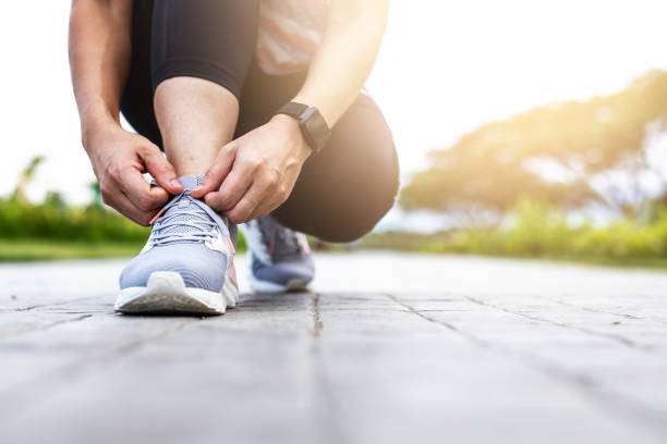 giovane donna che lega scarpe da jogging. - annodare foto e immagini stock